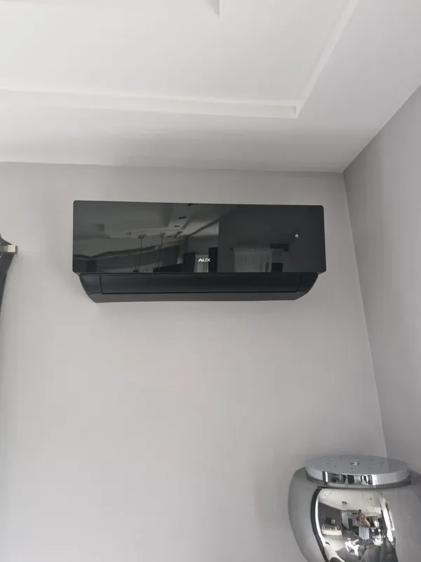 Czarny klimatyzator AUX zamontowany w rogu pokoju